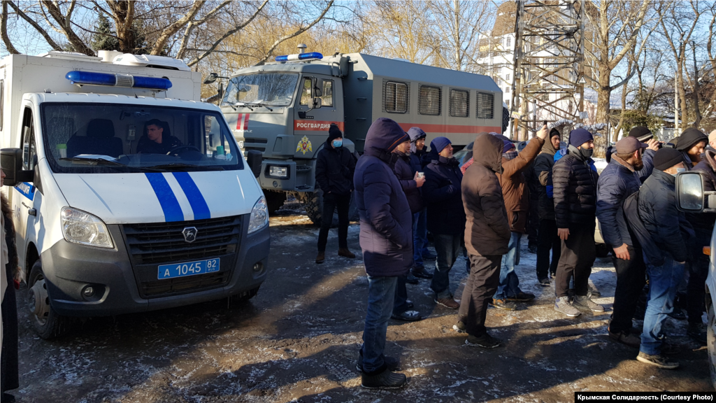 В задний двор суда заехали две ГАЗели. На улице дежурит КАМАЗ Росгвардии, машина ДПС и несколько служебных легковых машин полиции   