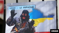 Плакат с изображением Владимира Путина в виде «зеленого человечка» во время акции «Крым – это Украина» у российского посольства в Киеве, 16 марта 2020 года