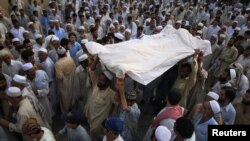 Residents carry the draped body of a suicide bomb victim to his grave in Pabbi, east of Peshawar, in July.