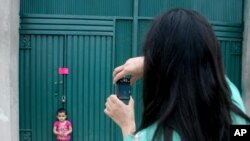 A woman photographs her daughter at a gate of Osama's compound