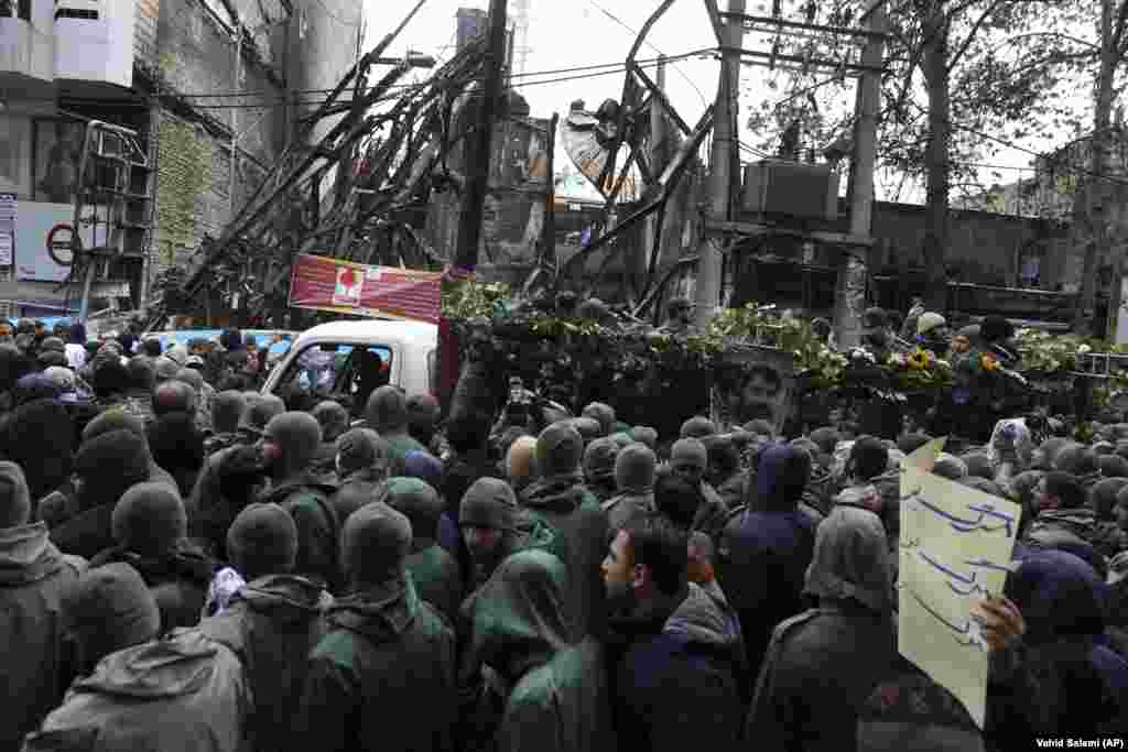 The funeral procession of a Islamic Revolutionary Guards Corps member killed in the recent protests in Shahriar, on the western edge of Tehran. Buildings in the background were also damaged in the protests. 