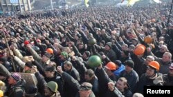 People cheer as they listen to police officers from Lviv who have joined the antigovernment protests during a rally on Independence Square in Kyiv on February 21.