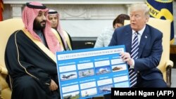 U.S. President Donald Trump (right) holds a defense sales chart with Saudi Arabia's Crown Prince Mohammed bin Salman in the White House on March 20.