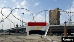An Egyptian flag is hung on barbed wire by opposition supporters on the front line near Tahrir Square in Cairo