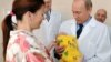 Vladimir Putin holds a newborn baby during a visit to a maternity hospital in Kaliningrad. The Russian president has made boosting the country's birthrate one of his core policies, but results have been mixed.