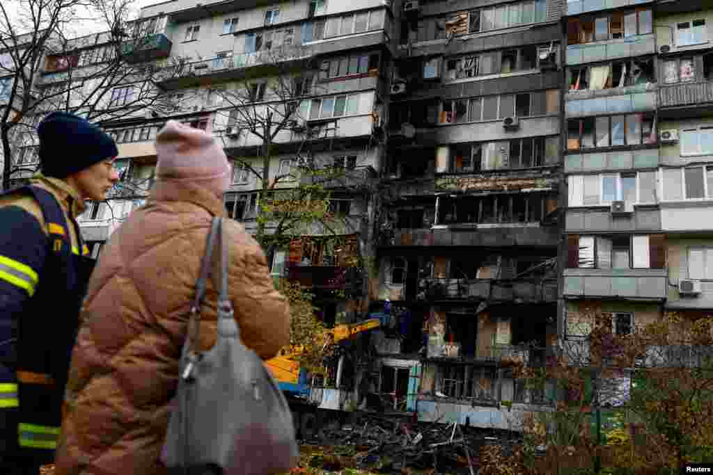 Психолог службы спасения разговаривает с жительницей, осматривая ее жилой дом, который был поврежден в результате ночного удара российского беспилотника, Киев, Украина, 26 октября 2025 года. REUTERS/Valentyn Ogirenko