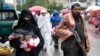 Kabul - o femeie afgană merge la piață în ținuta obligatorie - i se văd doar ochii și mâinile, în timp ce un luptător taliban stă de pază în Kabul (arhivă). 