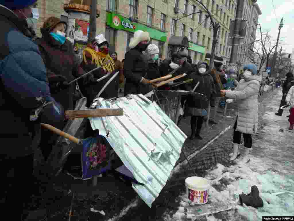 Протестующие бьют палками по железу. 