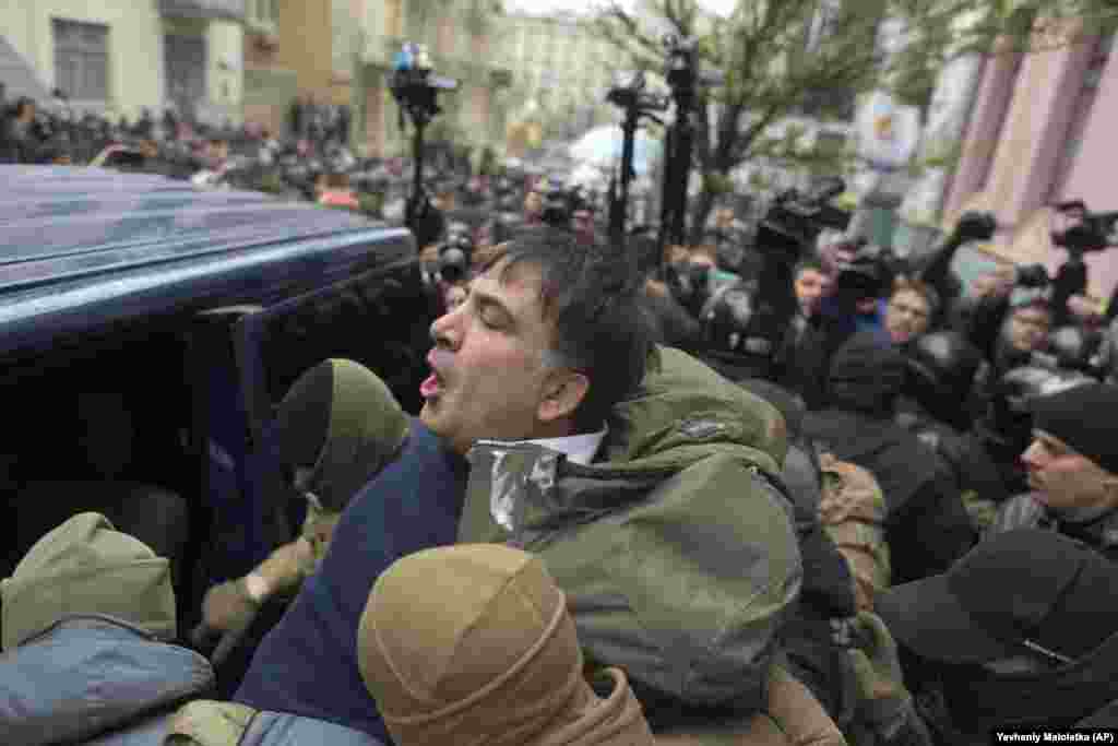 Police force Saakashvili into a police van. The official reason given for his arrest was that he was "plotting" against the Ukrainian authorities with the help of allies financed by exiled former Ukrainian President Viktor Yanukovych.