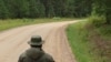 Un polițist de frontieră rus se uită la omologul său estonian în interiorul secțiunii „Cizma Saatse” a graniței comune a celor două țări.