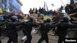 A line of riot police marches past pro-European integration protesters manning barricades on Independence Square in Kyiv on December 11.