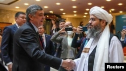 Russian envoy to Afghanistan Zamir Kabulov (left) shakes hands with a member of the Taliban delegation before talks in Moscow in October 2021. With the new deal, Moscow joins a short list of capitals willing to deal with the Taliban.