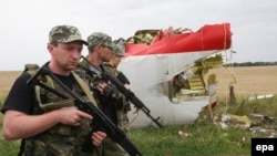 Armed Russia-backed militants walk past wreckage of Malaysia Airlines flight MH17 debris in July 2014.