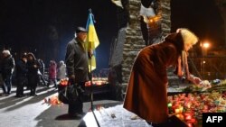 A woman lays a piece of bread next to candles during a ceremony in memory of the victims of the Holodomor famine in Kyiv on November 26.