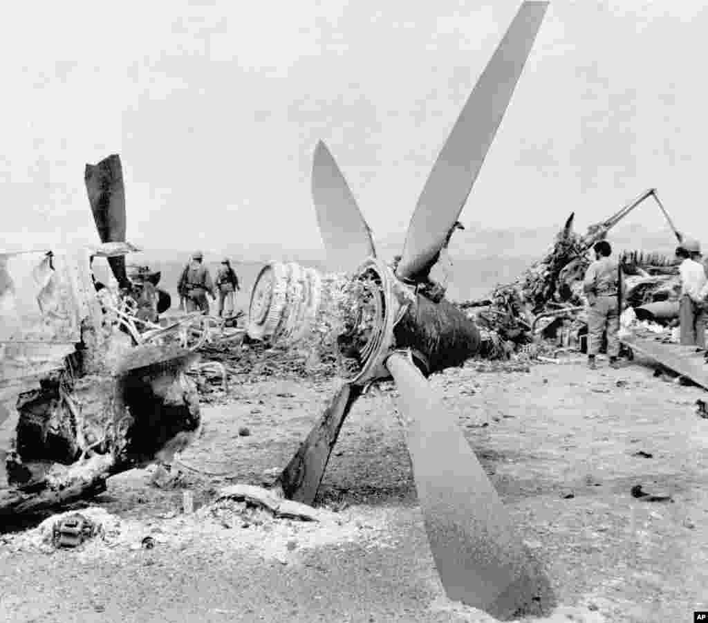The wreckage of a burned-out American C-130 Hercules cargo plane is inspected by Iranian troops in the Dasht-e Kavir desert, some 500 kilometers from Tehran, on April 26, 1980. An RH-53 helicopter collided with the plane during the attempt to free the American hostages. Mechanical problems and a sandstorm hampered the mission, and a U.S. commander advised Carter to abort. The accident happened after the abort order was given. The helicopter's rotor churned up sand, blocking visibility. Carter put much of the blame for his loss in the 1980 presidential election on his failure to free the hostages.
