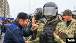 Участник митинга против границы между Чечней и Ингушетией и сотрудники полиции на центральной площади Магаса, октябрь 2018 года