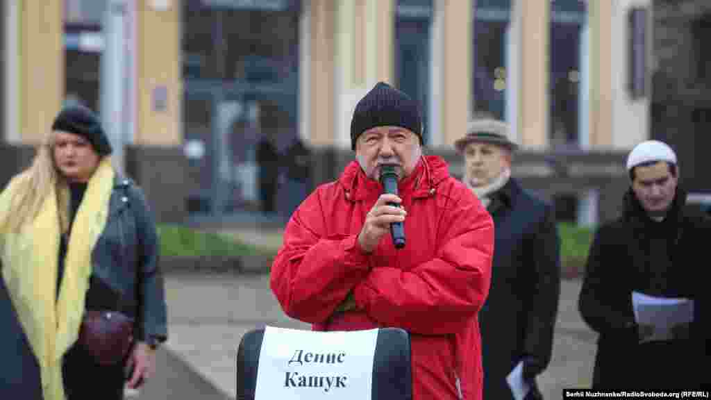 «Визнав провину через страх за рідних», – напишуть про Дениса Кашука. У грудні 2019 року російські силовики затримали Кашука. ФСБ інкримінує йому дві статті – 222 і 222.1 Кримінального кодексу Росії («незаконне придбання, передача, збут, зберігання, перевезення або носіння зброї, його основних частин, боєприпасів»). Суддя підконтрольного Росії Армянського міського суду Лариса Лихачова засудила сімферопольця Дениса Кашука до трьох років і восьми місяців колонії загального режиму. Вирок набере чинності протягом 10 днів. Біля стільця Кашука стоїть український письменник, журналіст та кіносценарист Андрій Курков.