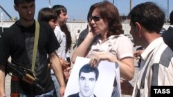 Наталья Эстемирова держит плакат "Верните Булата" на акции в поддержку сотрудника "Мемориала", пропавшего без вести в Чечне в 2007 году