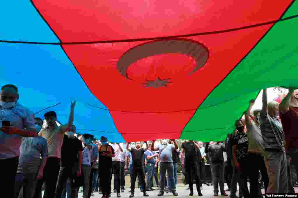 Azerbaijani mourners carry their nation's flag during the funeral march for Gashimov and Mirzayev.
