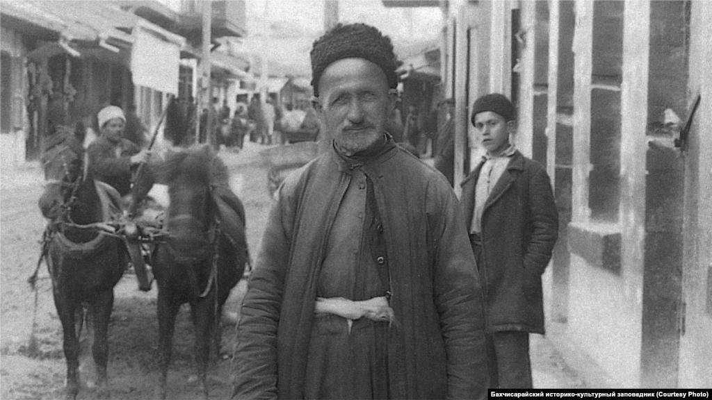 Житель Бахчисарая, 1920-ые. Мужчины покрывали голову низкой барашковой шапкой, тюбетейкой или феской. Рубаха с широкими рукавами заправлялась в широкие суконные шаровары и подпоясывалась широким кушаком. Поверх рубахи надевали короткий жилет с пуговицами, а сверху – длинный кафтан
