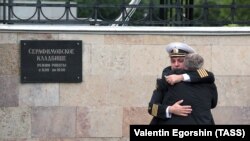 Russian Navy servicemen console each other ahead of a funeral service for 14 sailors who died in a submarine fire in the Barents Sea.