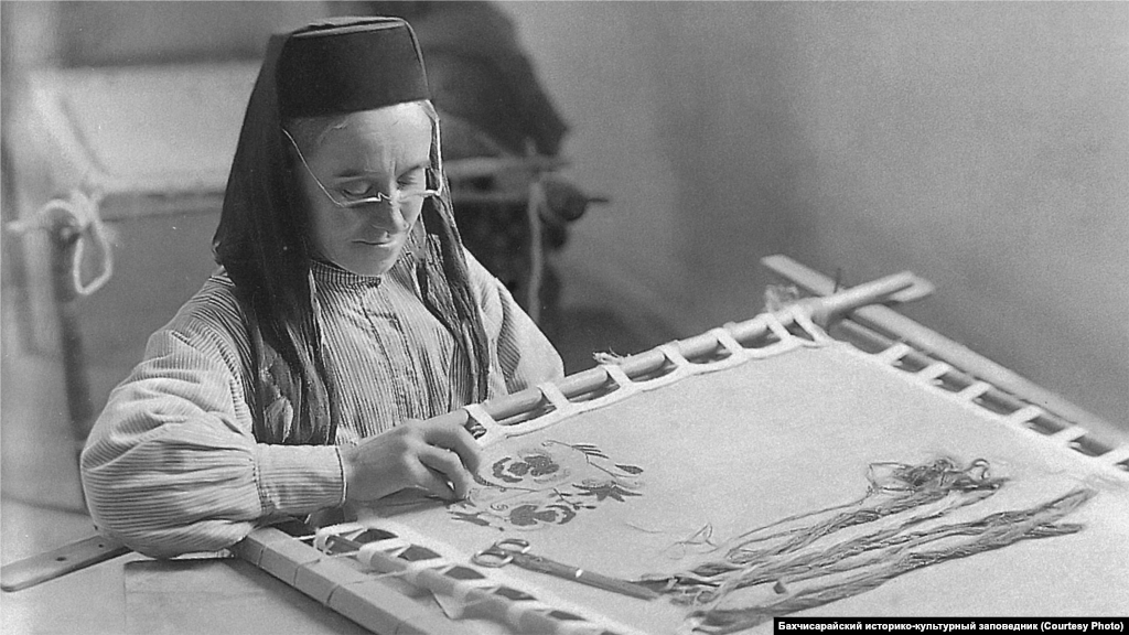 Вышивальщица. Бахчисарай, 1920-ые. Крымскотатарские одежду, обувь или текстиль невозможно представить без вышивки. Орнаменты различались по регионам – в вышивках Восточного Крыма заметны рыбы и лодки, степь отдавала предпочтение бордовому цвету. На Южном берегу изображали водоросли, преобладали сиреневый, фиолетовый и белый цвета