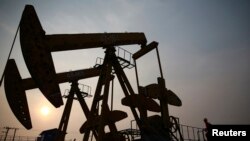 Un muncitor inspectează o pompă de extragere a petrolului din câmpul petrolier PetroChina, din Panjin