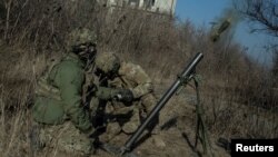 Ukrainian servicemen fire a mortar on the front line in Bakhmut.