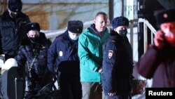 Kremlin critic Aleksei Navalny (in green jacket) is escorted by police officers after a court hearing in Khimki outside Moscow on January 18.