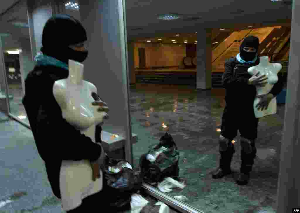 An opposition activist poses with a dummy in front of a mirror in Ukrainian House after protesters had taken over the building.