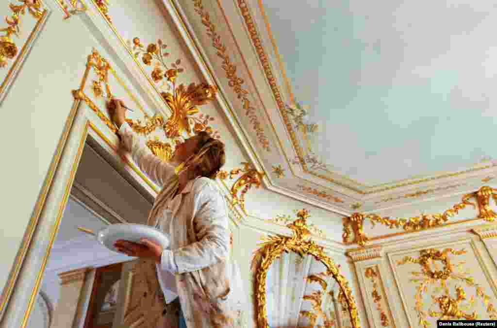 A painter touches up golden decoration inside the villa on June 11. 