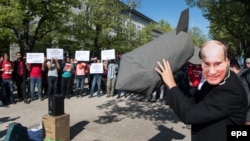Человек в маске Путина с макетом бомбы перед российским посольством в Берлине во время демонстрации против действий России в Сирии