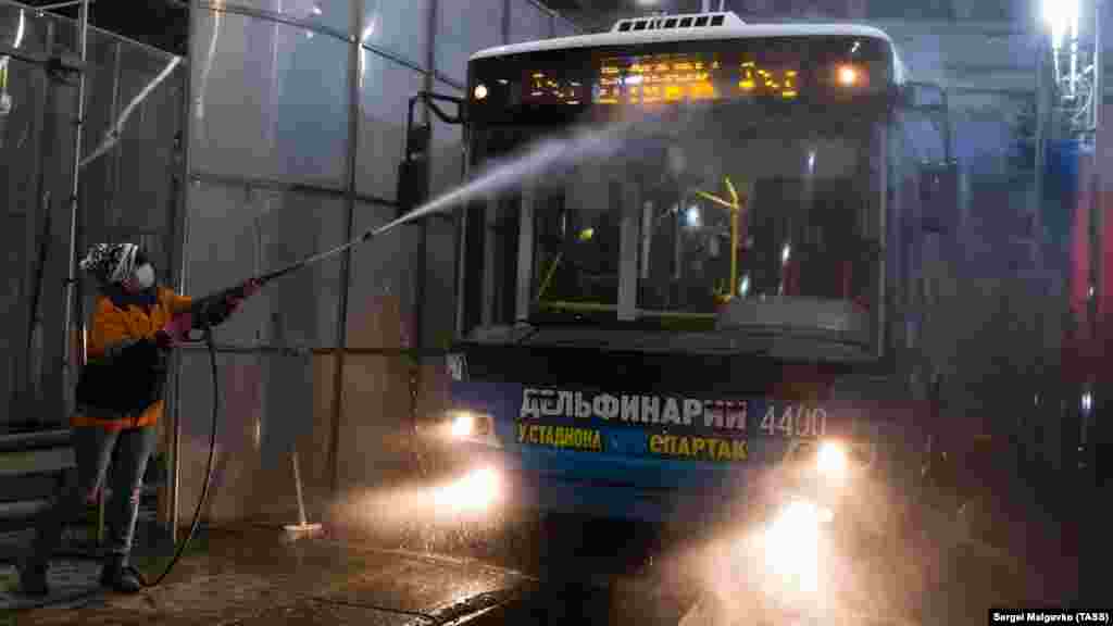 Сотрудница троллейбусного парка моет лобовое стекло 