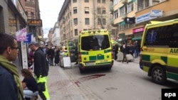 Emergency services help the injured near the scene where a truck crashed into a department store in central Stockholm in April. An Uzbek man has been charged with deliberately ramming the shop, killing four people.