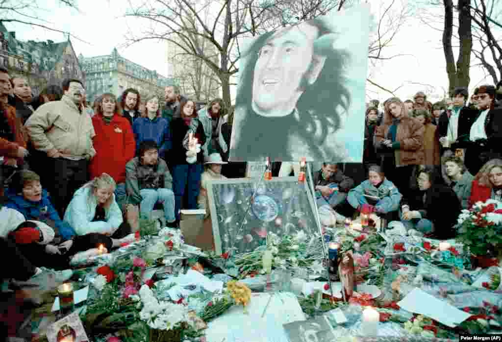 Люди собрались на «Strawberry Fields» в Центральном парке в десятую годовщину со дня убийства Джона Леннона, 8 декабря 1990 года. На заднем плане – многоквартирный дом «Дакота», где Леннон жил со своей семьей