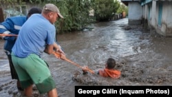 Two men work to save a resident who was swept away by floodwaters in Galati, Romania, on September 14.