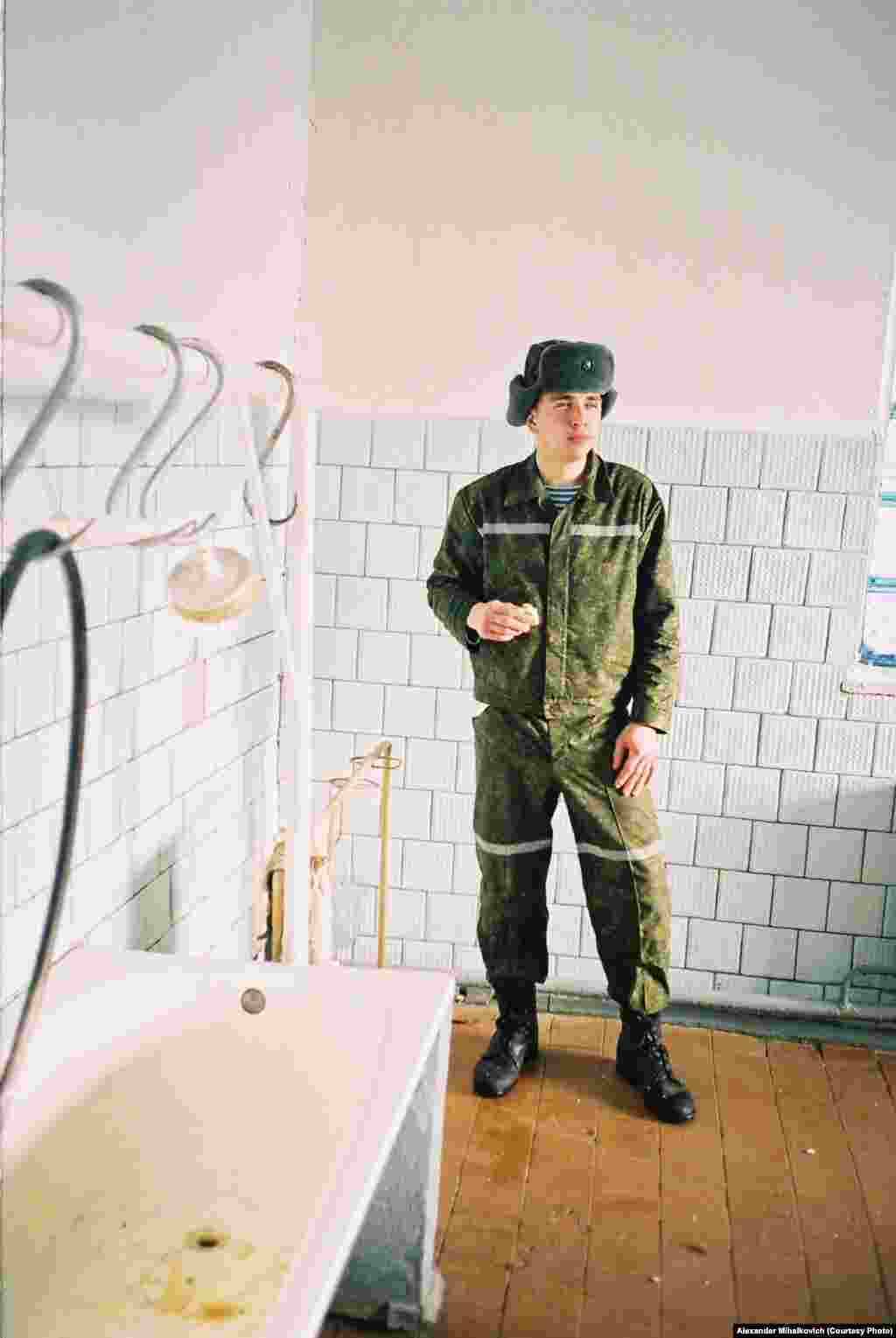 A soldier grabs a bite to eat while serving a 24-hour shift in the kitchen, where three people must wash the dishes for 1,200 others after each meal.