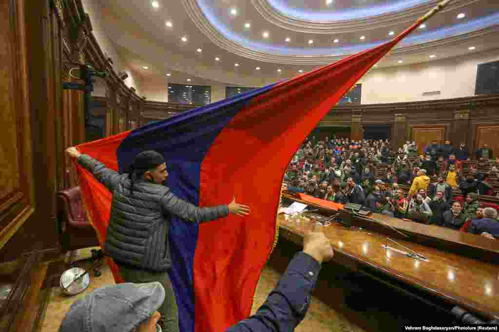 Protesters put up an Armenian flag inside of parliament. Objects were thrown, chairs smashed, and scuffles broke out at the podium. 
