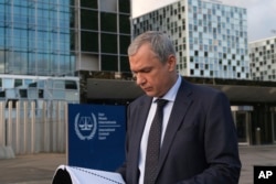 Haga, 7 noiembrie 2023: Activistul exilat Pavel Latușka citește dintr-un dosar după ce a prezentat Curții Penale Internaționale dovezi care susțin implicarea directă a lui Alexandr Lukașenko în transferul ilegal de copii în Belarus din orașele ocupate de Rusia în Ucraina.