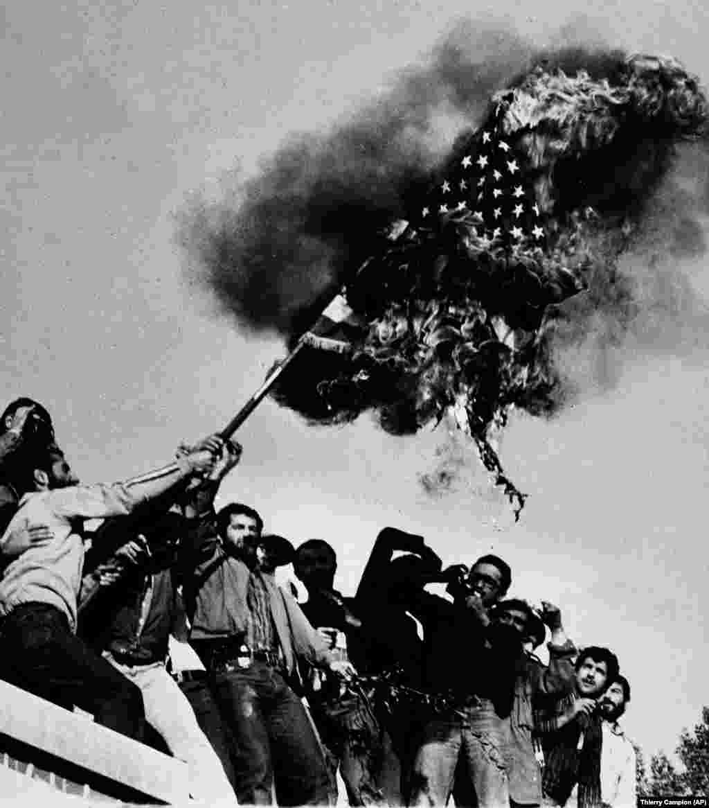 Demonstrators burn an American flag on November 9, 1979, atop the wall of the U.S. Embassy in Tehran. Weeks after the shah's departure, Ayatollah Ruhollah Khomeini returned from his 14-year exile in Paris to jubilant crowds. In March 1979, a referendum showed an overwhelming margin in favor of replacing the monarchy with an Islamic government.