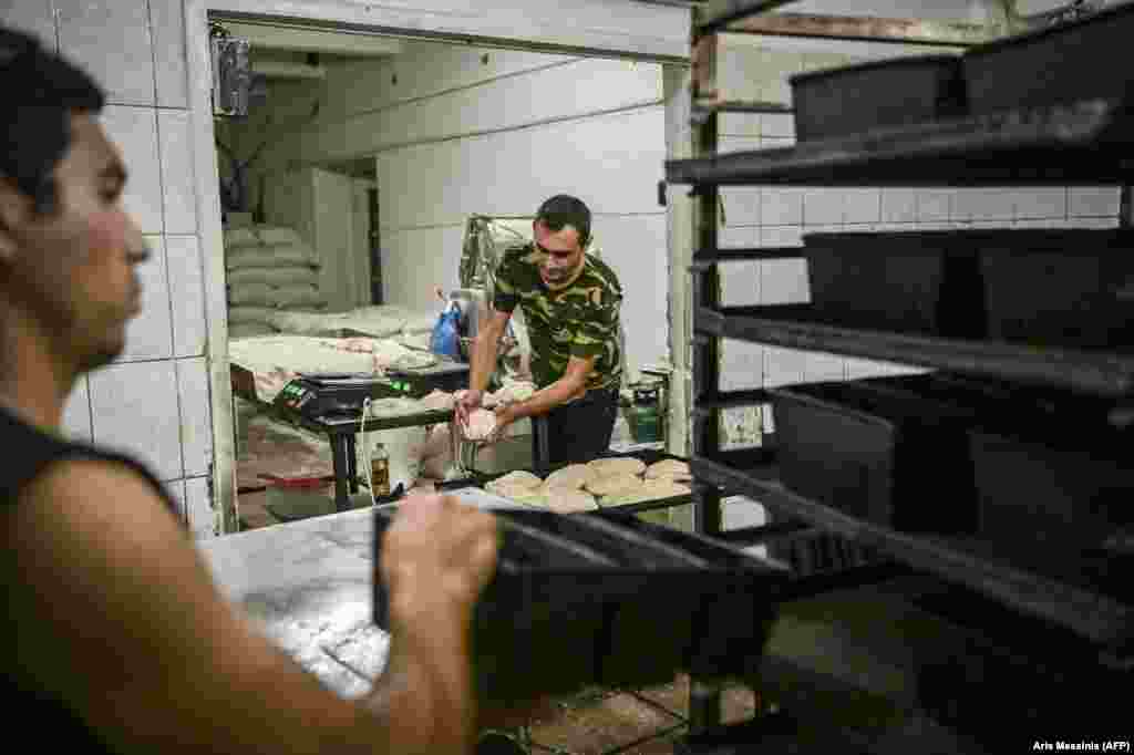 Workers prepare dough for the oven.  