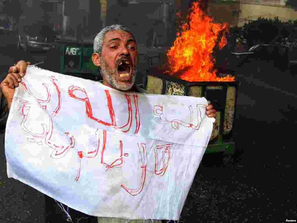 A protester shouts in front of a burning barricade during a demonstration in Cairo on January 28.