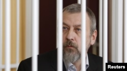 Former opposition presidential candidate Andrey Sannikau sits in a cage during a court hearing in Minsk last year.