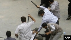 Men in civilian clothes beat a protester during a demonstration on June 14.