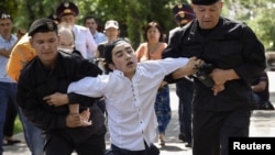 Kazakh police officers detain an opposition supporter attempting to stage a protest rally in Almaty on June 23.