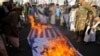 People gather near burning Israeli and U.S. flags as supporters of the Huthi movement rally to denounce air strikes launched by the United States and Britain on Huthi targets, in Sanaa, Yemen, on January 12.