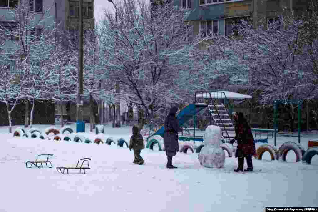 Пока дети играют, взрослые лепят снеговика. 