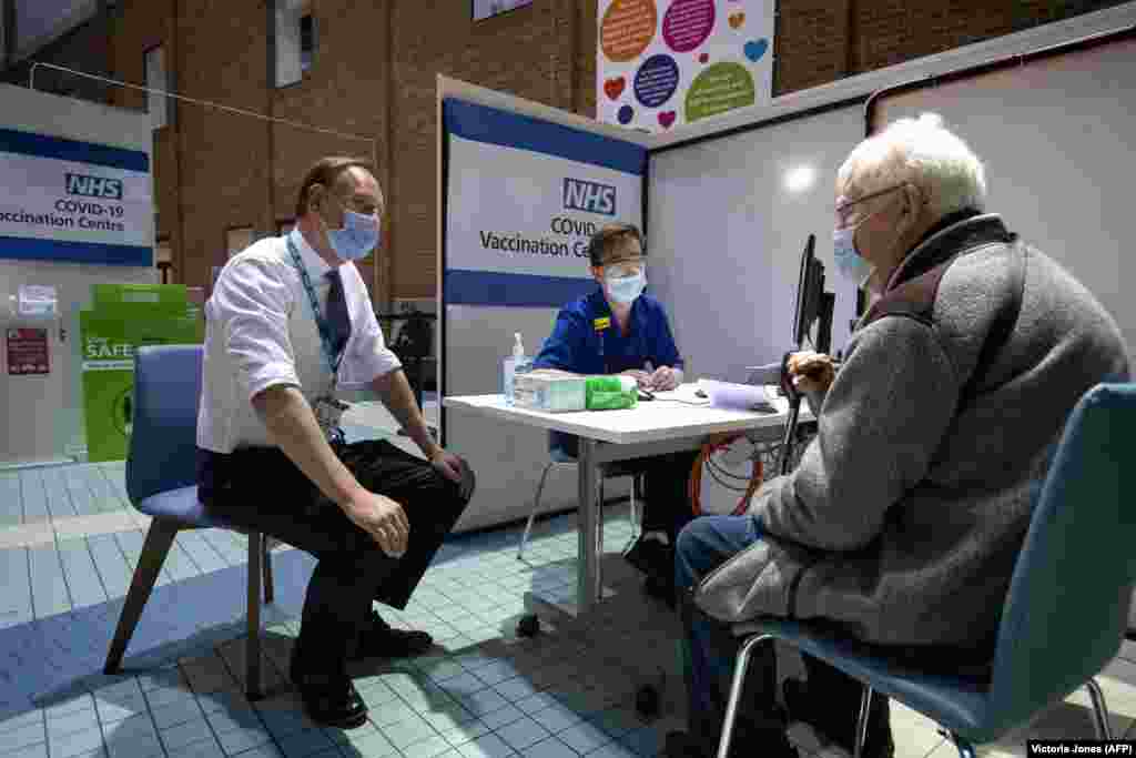Саймон Стивенс (слева), исполнительный директор NHS (Национальная служба здравоохранения Соединенного Королевства), беседует с пациентом, который прибыл в центр вакцинации, чтобы получить дозу вакцины Pfizer/BioNTech COVID-19 в больнице Гая. Лондон, Великобритания, 8 декабря 2020 года