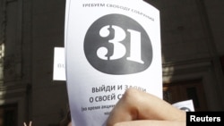 An opposition party supporter holds up a leaflet with the number '31' on it during a protest rally in Moscow