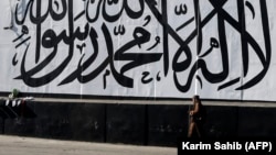 A man walks past a wall mural depicting the Taliban flag in Kabul.
